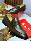 Black and brown Salvatore Ferragamo crocodile-embossed leather loafers with Gancini hardware displayed on red boxes with gold horse statue.