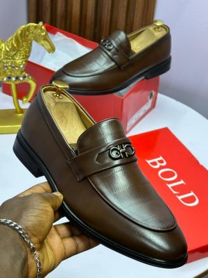 Black and brown Salvatore Ferragamo crocodile-embossed leather loafers with Gancini hardware displayed on red boxes with gold horse statue.