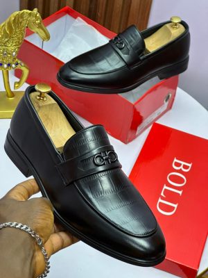 Black and brown Salvatore Ferragamo crocodile-embossed leather loafers with Gancini hardware displayed on red boxes with gold horse statue.