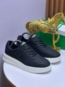 Black Lacoste pebbled leather sneakers with white sole displayed on white surface with gold horse statue and green box.