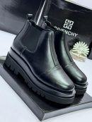 Givenchy men's black leather Chelsea boots with chunky platform sole, held by gloved hand against branded box background.