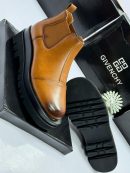 Givenchy men's black leather Chelsea boots with chunky platform sole, held by gloved hand against branded box background.