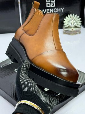 Givenchy men's black leather Chelsea boots with chunky platform sole, held by gloved hand against branded box background.
