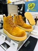 Balenciaga men's mustard yellow suede combat boots with tonal laces, side zipper, and thick crepe sole, displayed on grey shoebox with branded cards and accessories.