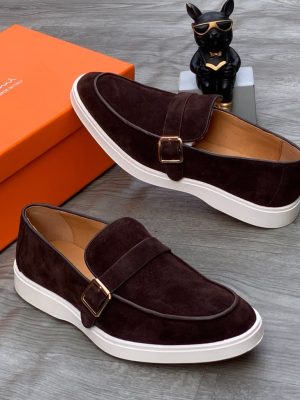 Santoni men's burgundy suede monk strap sneakers with gold buckle and white rubber sole, displayed with orange branded shoebox on grey wood floor.