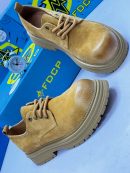 FDCP men's mustard distressed suede chunky boots with rope laces and thick ridged platform sole, displayed with blue branded shoebox and vintage alarm clock on white surface.