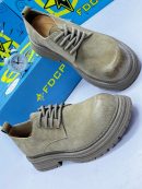 FDCP men's sage green distressed suede chunky boots with rope laces and thick ridged platform sole, displayed with blue branded shoebox and vintage alarm clock on white surface.