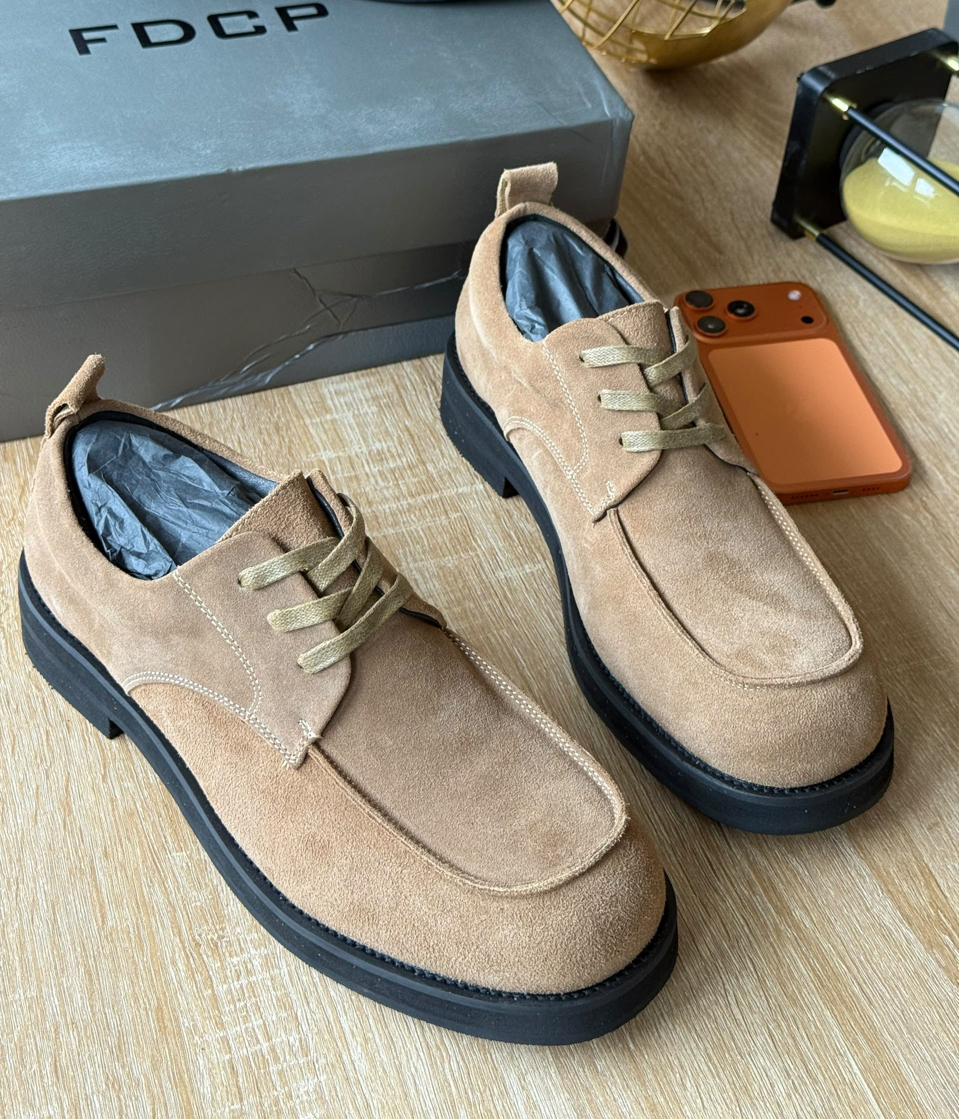 FDCP beige suede derby shoes FDCP men's beige suede derby shoes with tonal laces and thick black rubber sole, displayed on wooden surface with grey branded shoebox and orange phone.