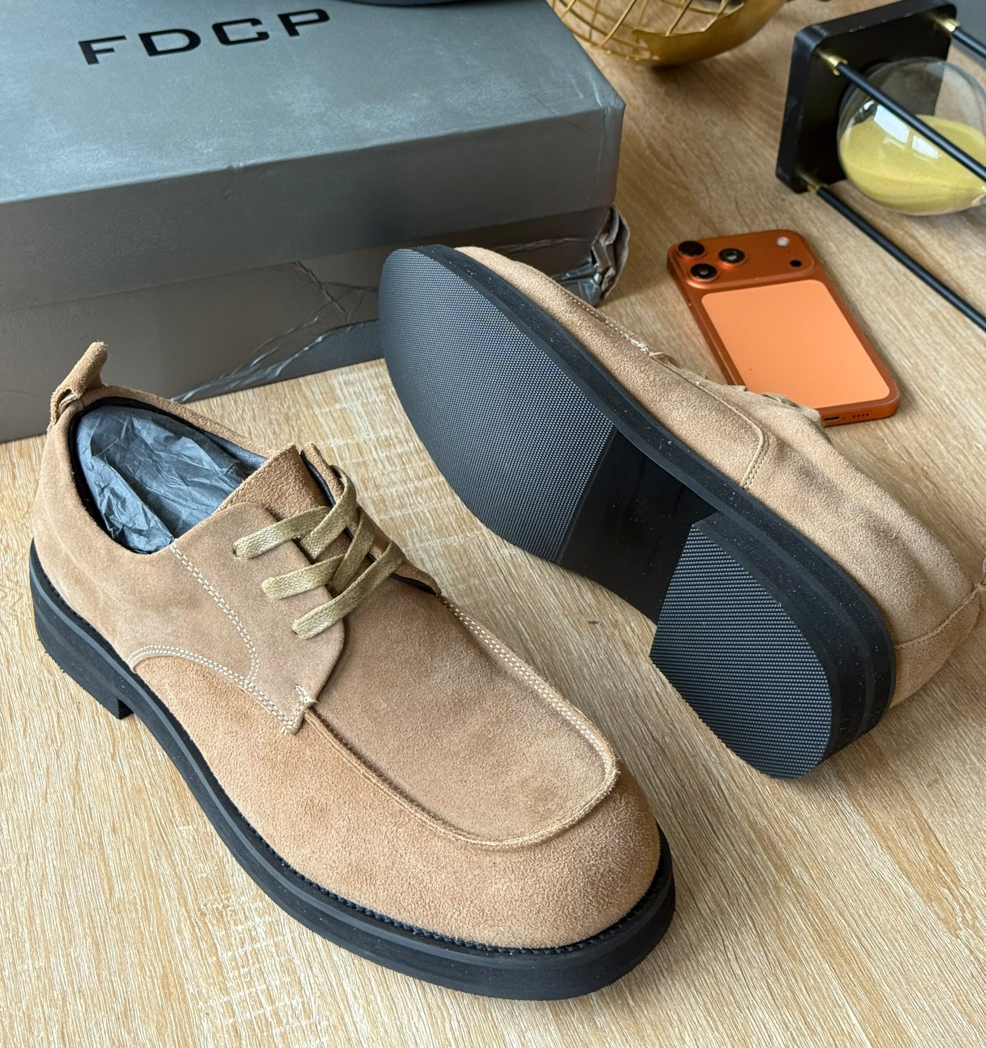 FDCP beige suede derby shoes FDCP men's beige suede derby shoes with tonal laces and thick black rubber sole, displayed on wooden surface with grey branded shoebox and orange phone.