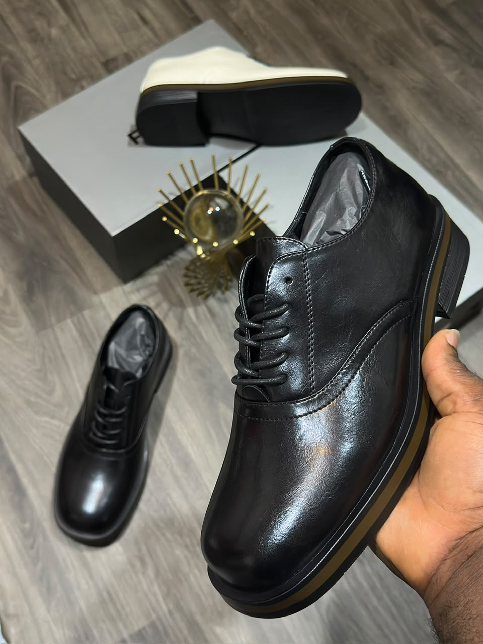 Men's luxury leather oxford shoe Men's luxury black leather oxford dress shoes with a thick sole and tan midsole accent resting on a marble surface.