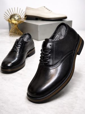 Men's luxury black leather oxford dress shoes with a thick sole and tan midsole accent resting on a marble surface.