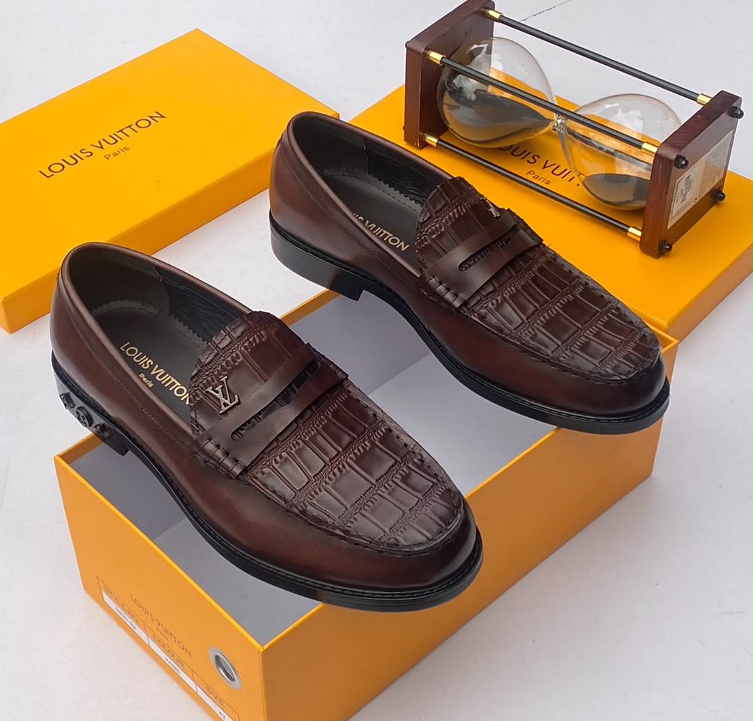 Louis Vuitton chocolate brown croc-embossed penny loafers Men's chocolate brown Louis Vuitton crocodile-embossed penny loafers with metal LV hardware and rubber-injected heel, displayed with branded orange shoebox and hourglass on white surface.