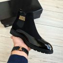 Black men's patent leather and suede Chelsea boots with gold Greek key side panel and chunky rubber lug sole.