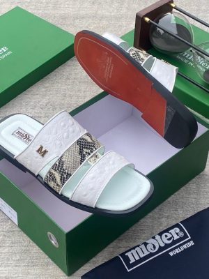 miSter men’s white and snakeskin triple-strap slides with gold “M” hardware and red-accented sole, displayed beside green branded box and hourglass on textured surface.