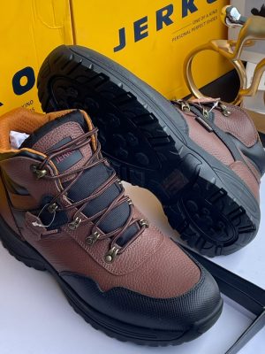 Jerkoo men's brown pebbled leather hiking boots with black rubber toe cap, deep lug sole, and metal eyelets, displayed with yellow branded box and gold bicycle sculpture.