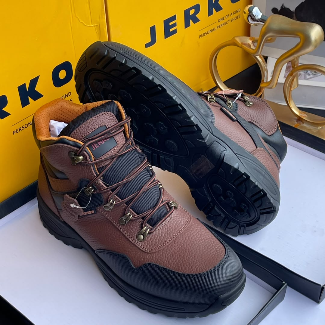 Jerkoo leather hiking boots Jerkoo men's brown pebbled leather hiking boots with black rubber toe cap, deep lug sole, and metal eyelets, displayed with yellow branded box and gold bicycle sculpture.