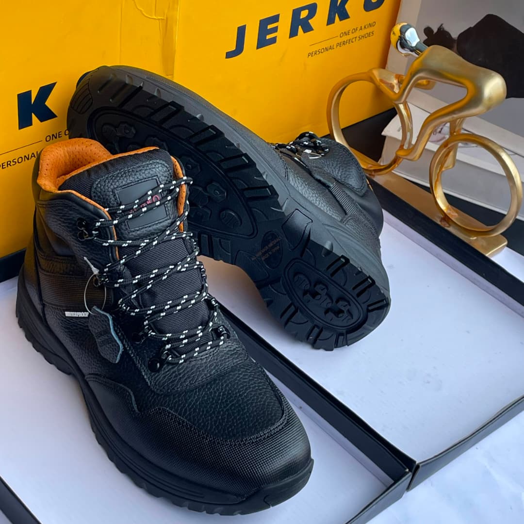 Jerkoo leather hiking boots Jerkoo men's brown pebbled leather hiking boots with black rubber toe cap, deep lug sole, and metal eyelets, displayed with yellow branded box and gold bicycle sculpture.