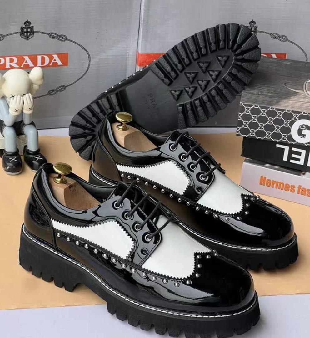 Bold black-and-white patent leather derby shoes Men's black and white patent leather spectator derby shoes with silver stud detailing and thick black chunky lug sole, displayed with shoe trees and branded boxes.
