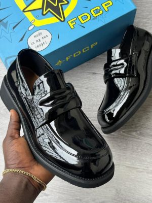 FDCP men's burgundy high-gloss patent leather penny loafers with thick chunky black rubber sole, held in hand with branded blue FDCP shoebox in background.