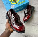 FDCP men's burgundy high-gloss patent leather penny loafers with thick chunky black rubber sole, held in hand with branded blue FDCP shoebox in background.