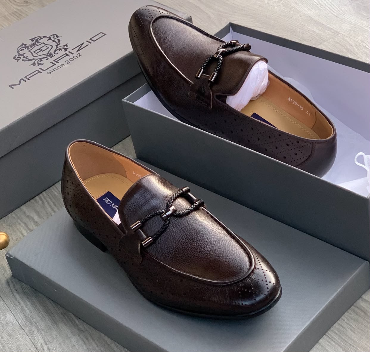 Malraizio braided leather loafers Men's dark chocolate Malraizio braided leather loafers with perforated detailing, gunmetal hardware, and rubber sole, displayed in grey branded shoebox on wood floor.