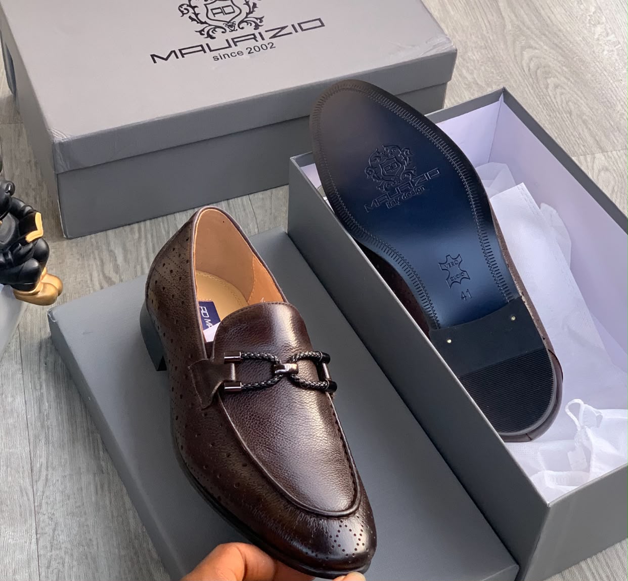 Malraizio braided leather loafers Men's dark chocolate Malraizio braided leather loafers with perforated detailing, gunmetal hardware, and rubber sole, displayed in grey branded shoebox on wood floor.