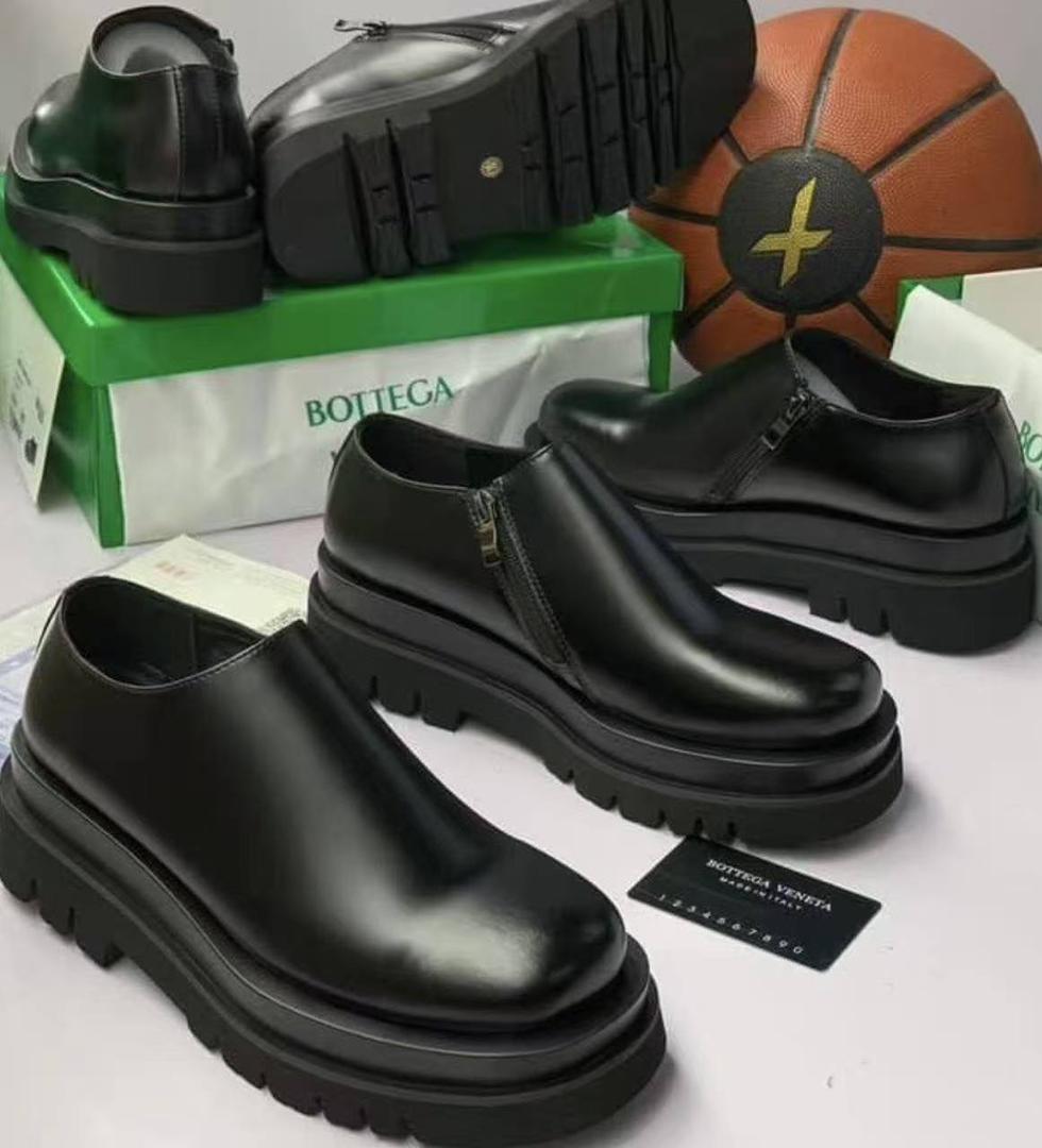 Premium black leather chunky Chelsea boots Men's black leather chunky Chelsea boots with side zipper and thick ridged platform sole, displayed on grey block against marble background.