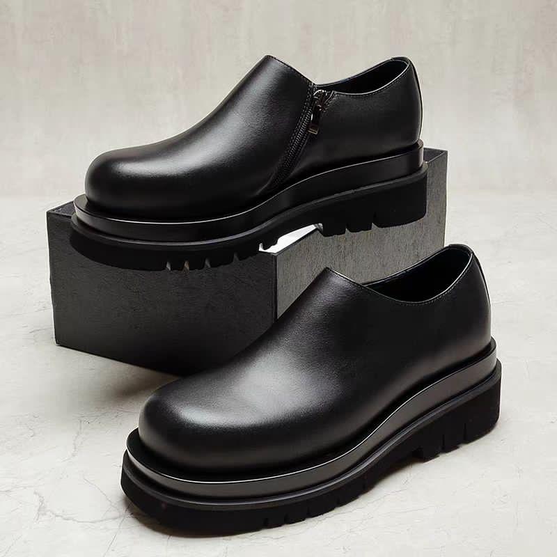 Premium black leather chunky Chelsea boots Men's black leather chunky Chelsea boots with side zipper and thick ridged platform sole, displayed on grey block against marble background.