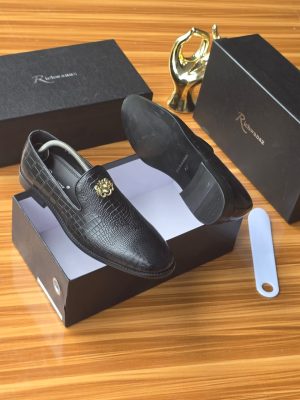 Men's luxury black crocodile-embossed leather loafers with gold medallion hardware resting on black Richwanaz shoeboxes.