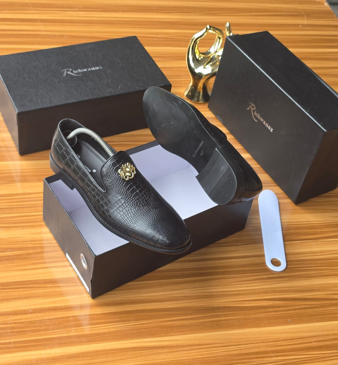 Bold black Richwanaz crocodile-embossed loafers Men's luxury black crocodile-embossed leather loafers with gold medallion hardware resting on black Richwanaz shoeboxes.