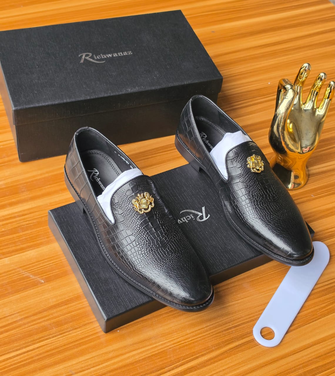 Bold black Richwanaz crocodile-embossed loafers Men's luxury black crocodile-embossed leather loafers with gold medallion hardware resting on black Richwanaz shoeboxes.