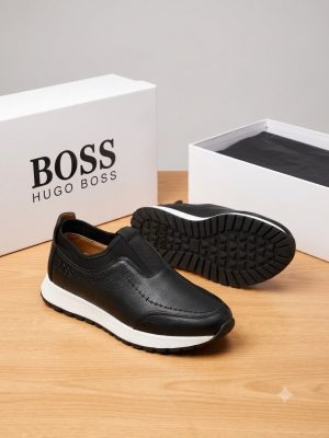 Hugo Boss men's brown pebbled leather slip-on sneakers with black elastic panels and white midsole, displayed with branded white shoebox on a grey surface.