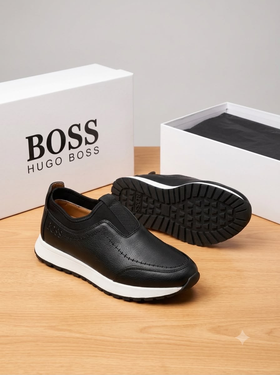 Hugo Boss pebbled leather slip-on sneakers Hugo Boss men's brown pebbled leather slip-on sneakers with black elastic panels and white midsole, displayed with branded white shoebox on a grey surface.