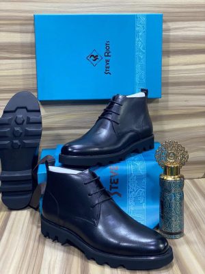 Men's black leather Steve Riots combat boots with thick ridged platform sole, displayed on wooden surface with branded blue shoebox and decorative perfume bottle.