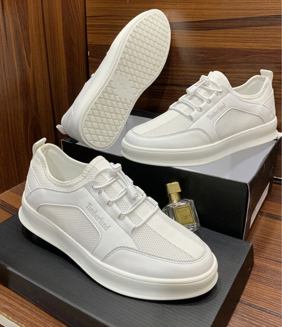 Timberland all-white leather and mesh sneakers Timberland men's all-white leather and mesh lace-up sneakers with thick white rubber sole, displayed on black shoeboxes with a perfume bottle.
