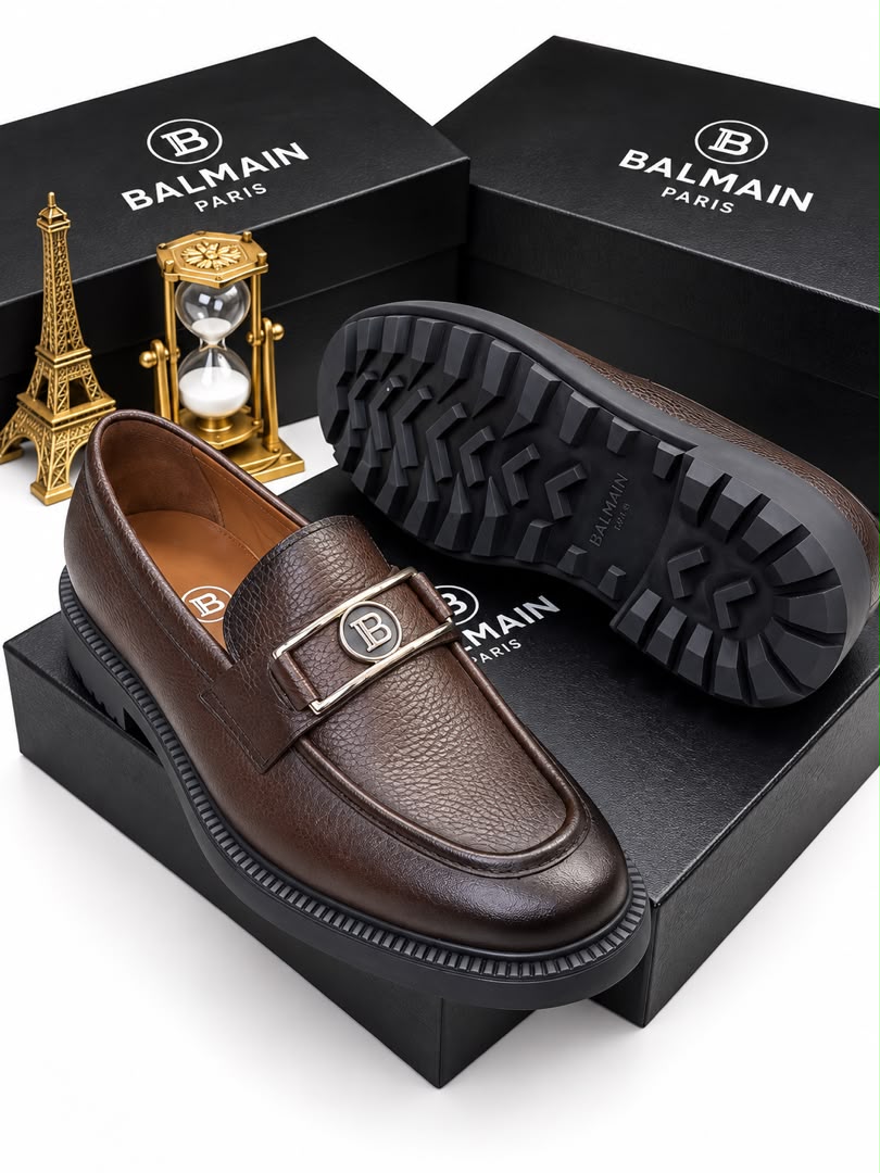Dark brown men's pebbled leather Balmain loafers with silver "B" hardware and chunky black rubber lug sole.