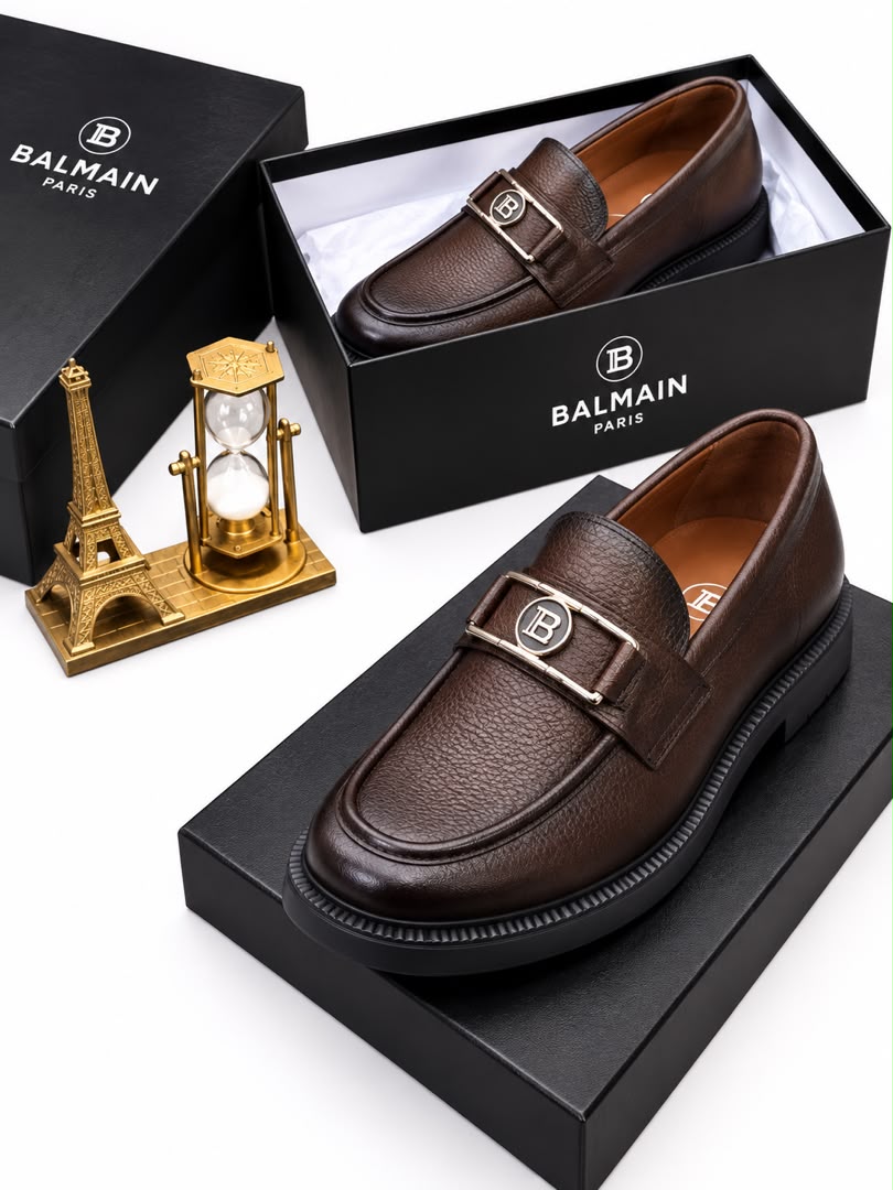 Dark brown men's pebbled leather Balmain loafers with silver "B" hardware and chunky black rubber lug sole.