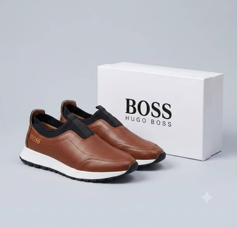 Hugo Boss pebbled leather slip-on sneakers Hugo Boss men's brown pebbled leather slip-on sneakers with black elastic panels and white midsole, displayed with branded white shoebox on a grey surface.