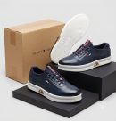 Navy men's leather Tommy Hilfiger sneakers with red and white striped detailing and white rubber sole.